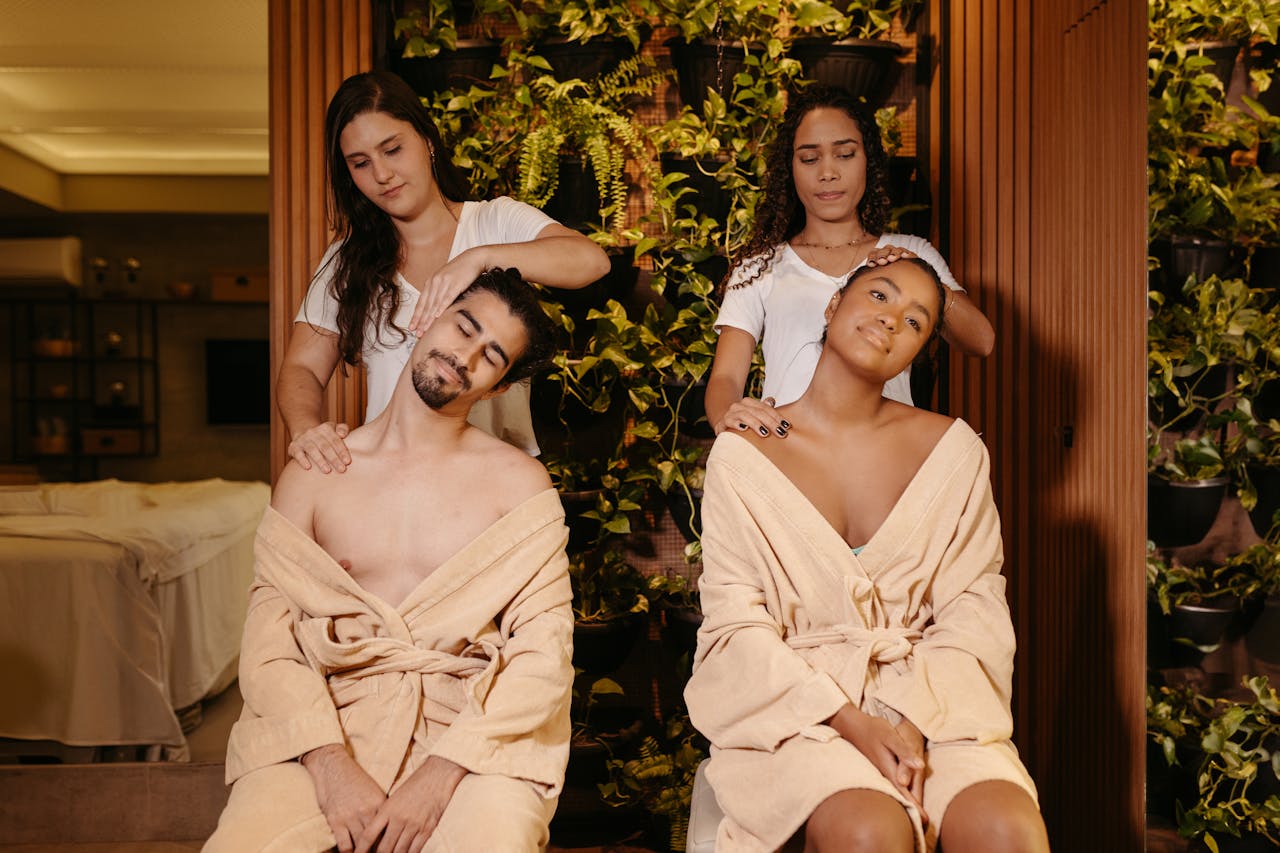 Two massage therapists perform synchronized strokes during a couples massage.