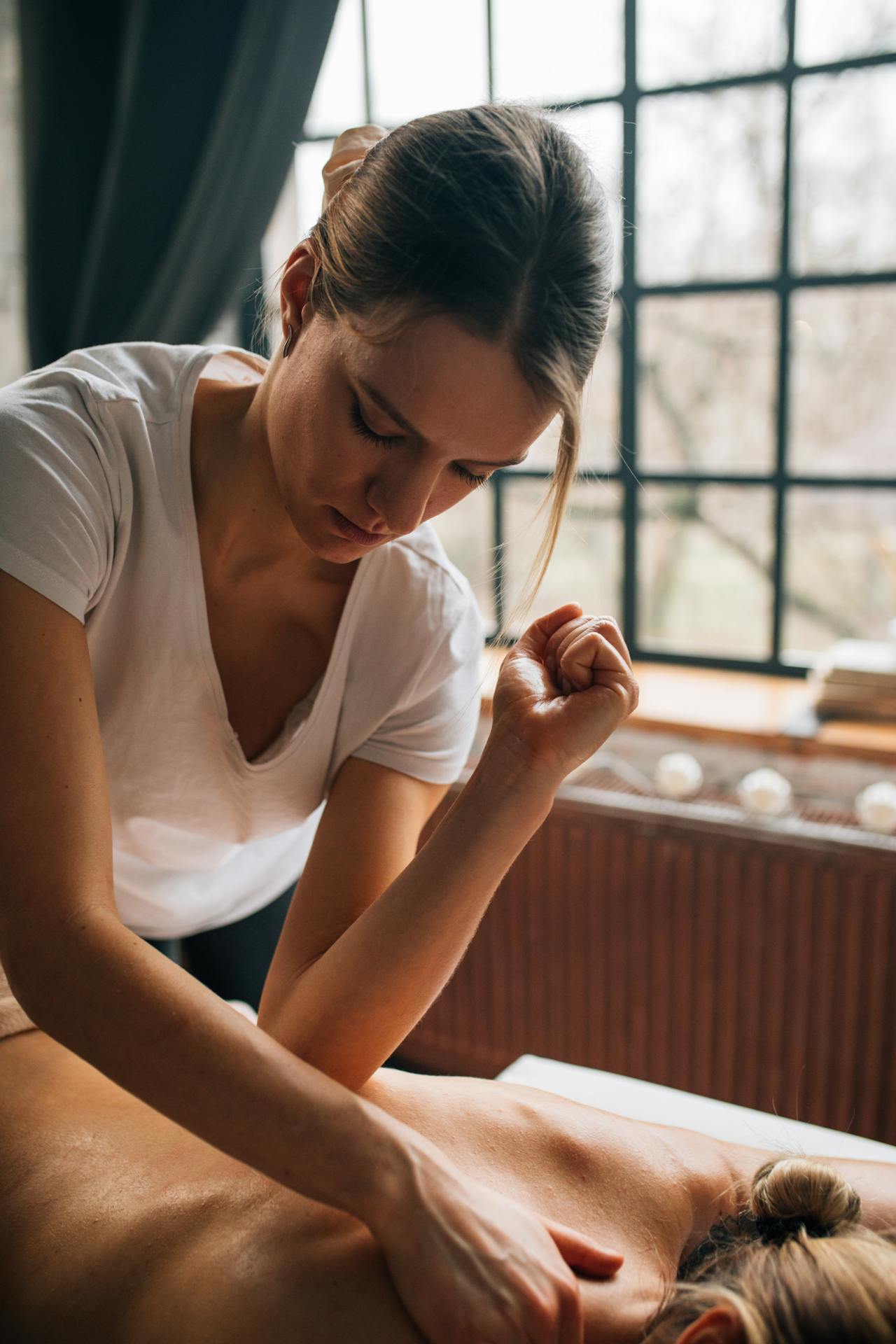 A therapist uses their elbow to apply slow, deliberate pressure during a deep tissue massage.