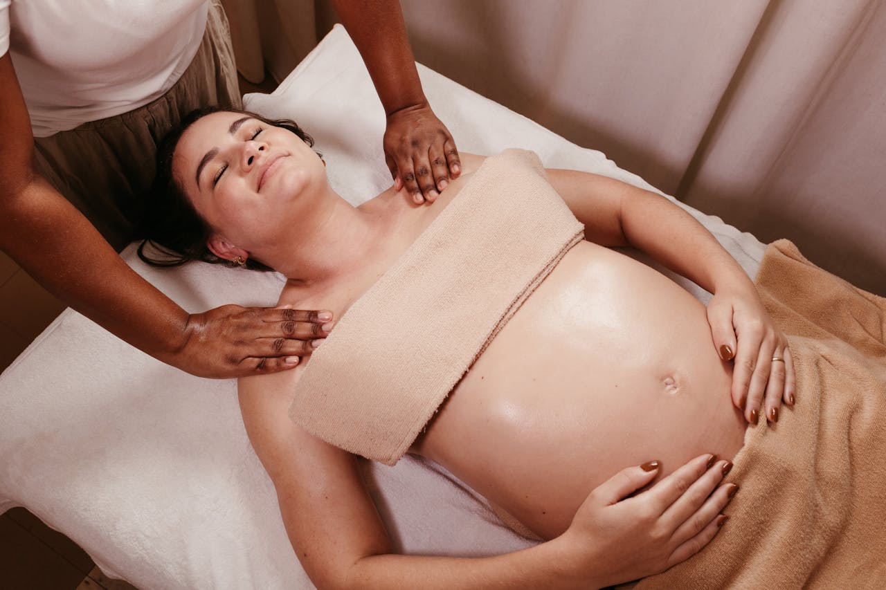 A massage therapist provides a gentle, caring touch to an expecting mother during a prenatal massage consultation.