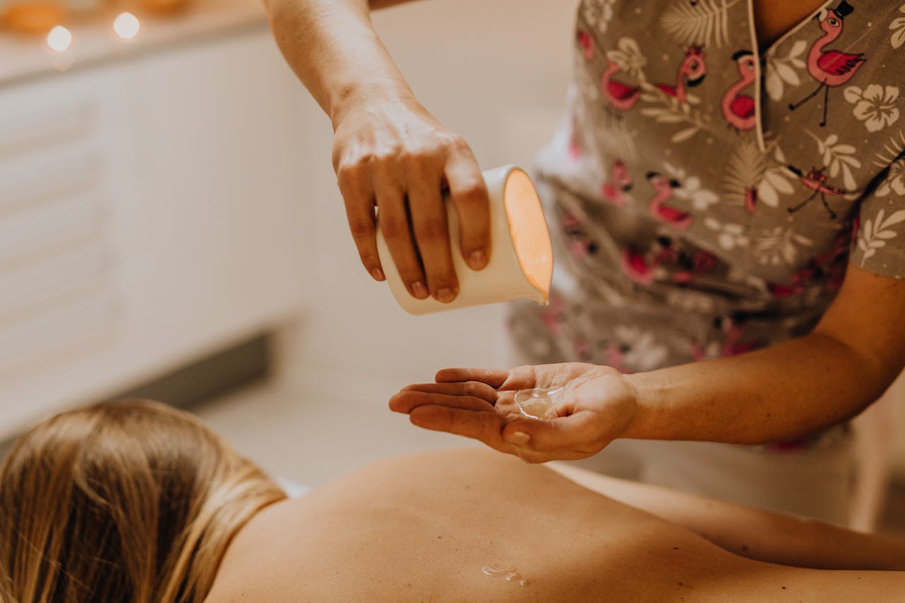 A licensed massage therapist is starting a spa treatment session with oil.
