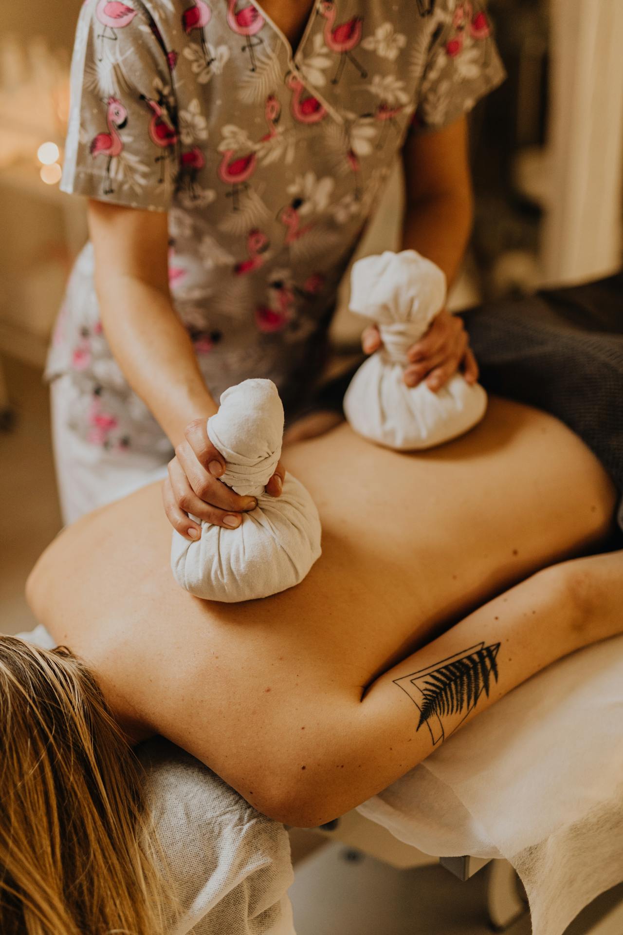 A licensed massage therapist applying cold packs to a client’s back during cryotherapy treatment.